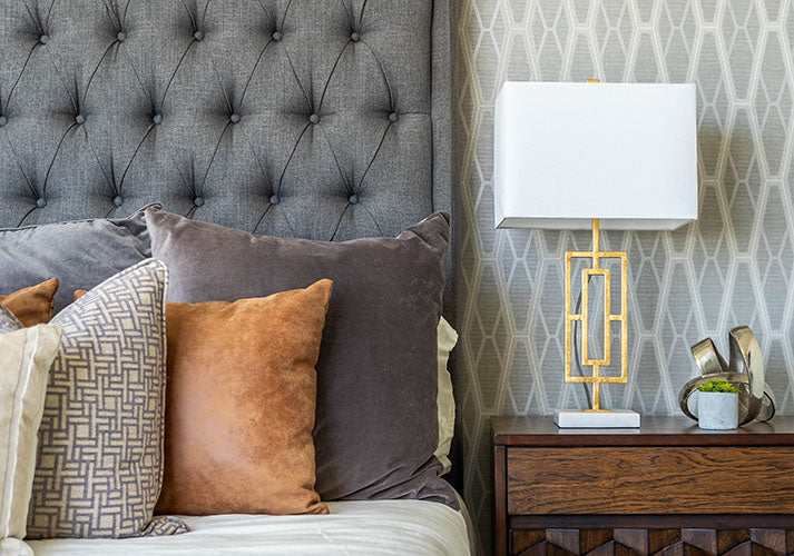 Staged bedroom - tufted bed with decorative pillows. Nightstand with lamp and decor