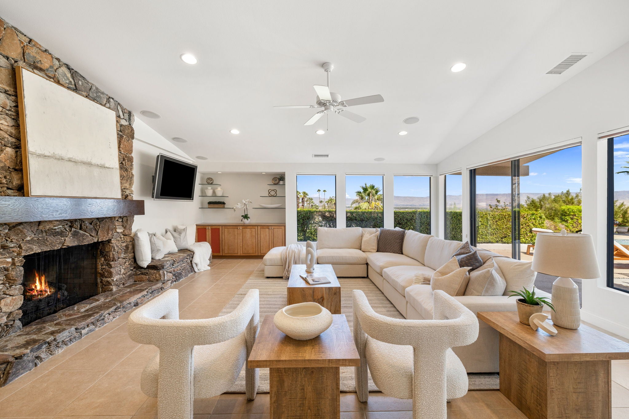 Modern living room with a fireplace, sectional sofa, and large windows.
