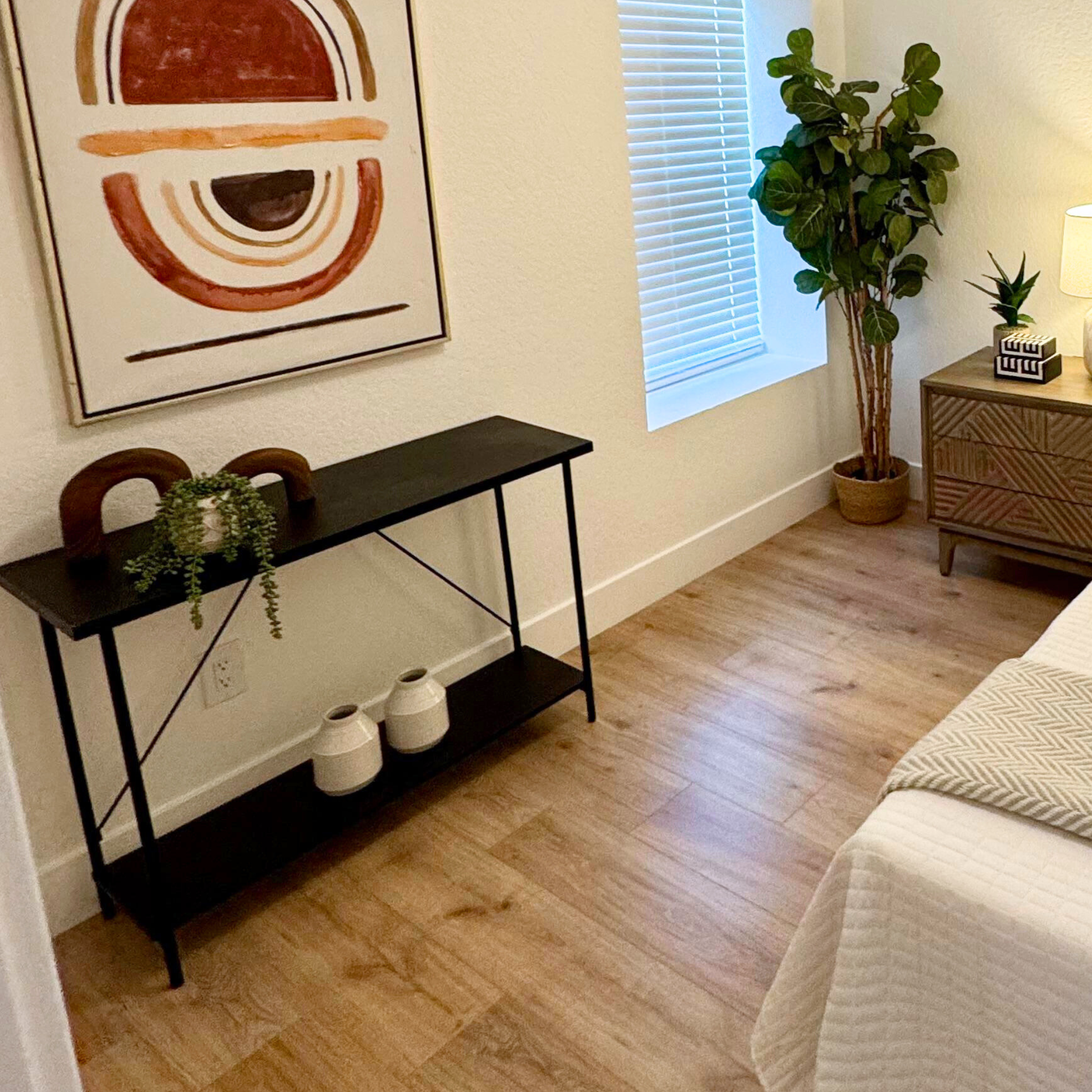 Black and wood two tier console in a staged bedroom