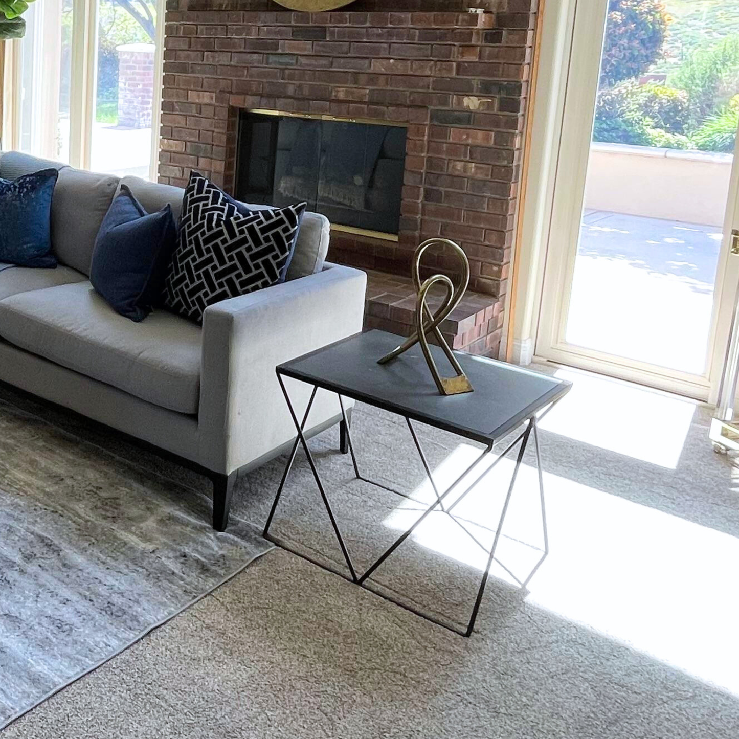 Living room with a gray sofa, decorative pillows, a coffee table, and a brick fireplace.