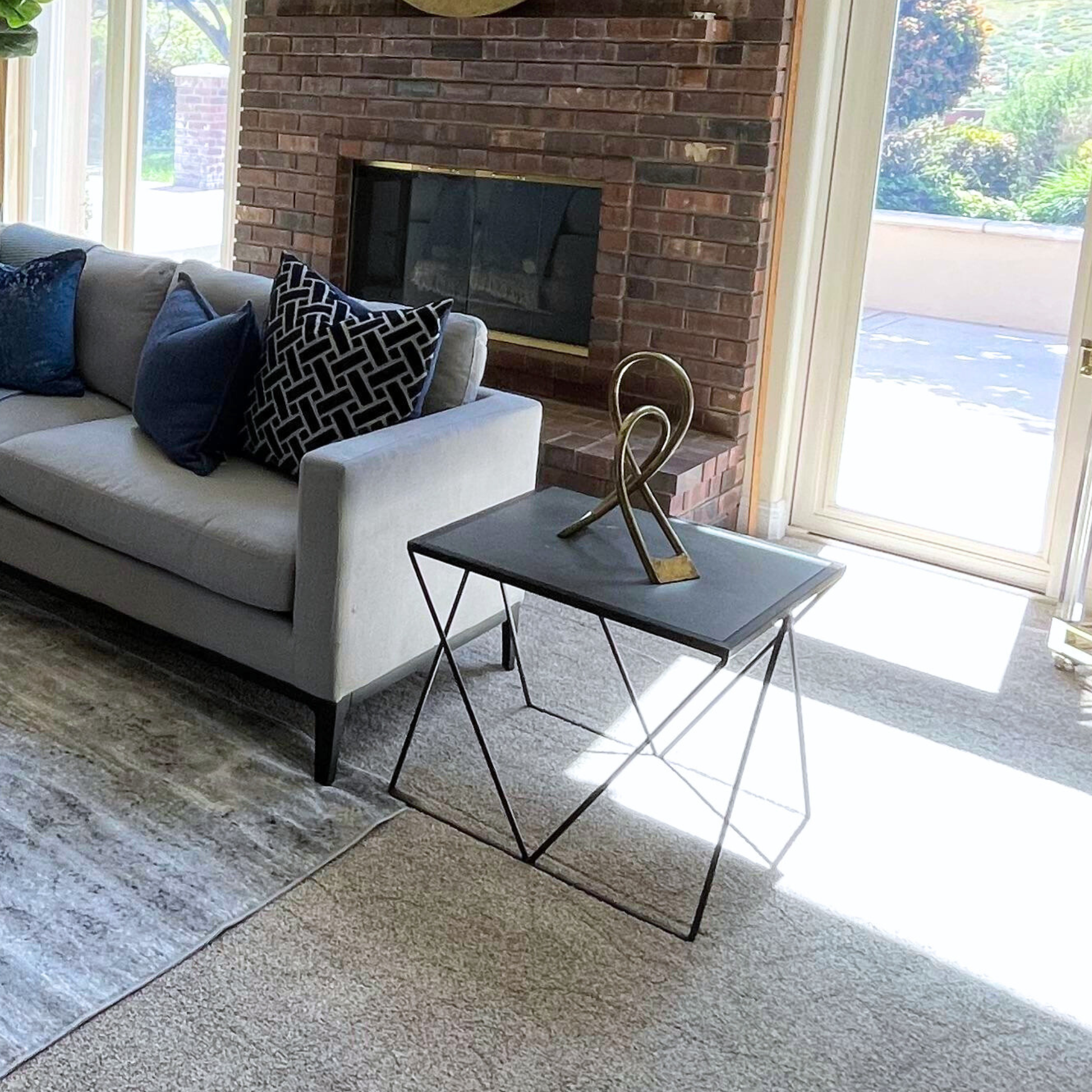 Living room with a gray sofa, decorative pillows, a coffee table, and a brick fireplace.