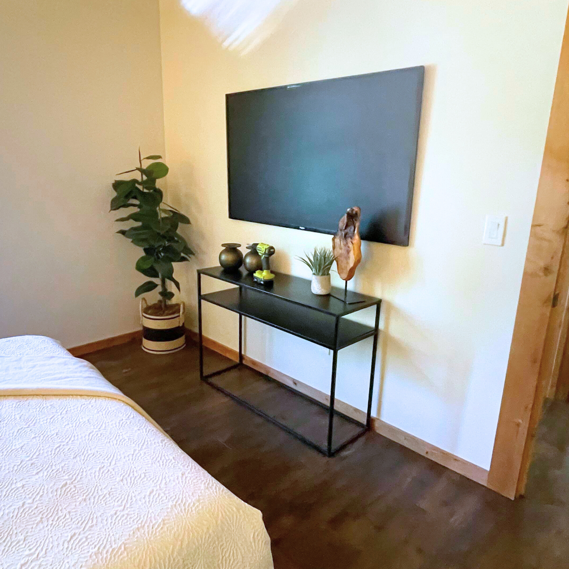 Black Metal console table in a staged bedroom with a TV on the wall. 