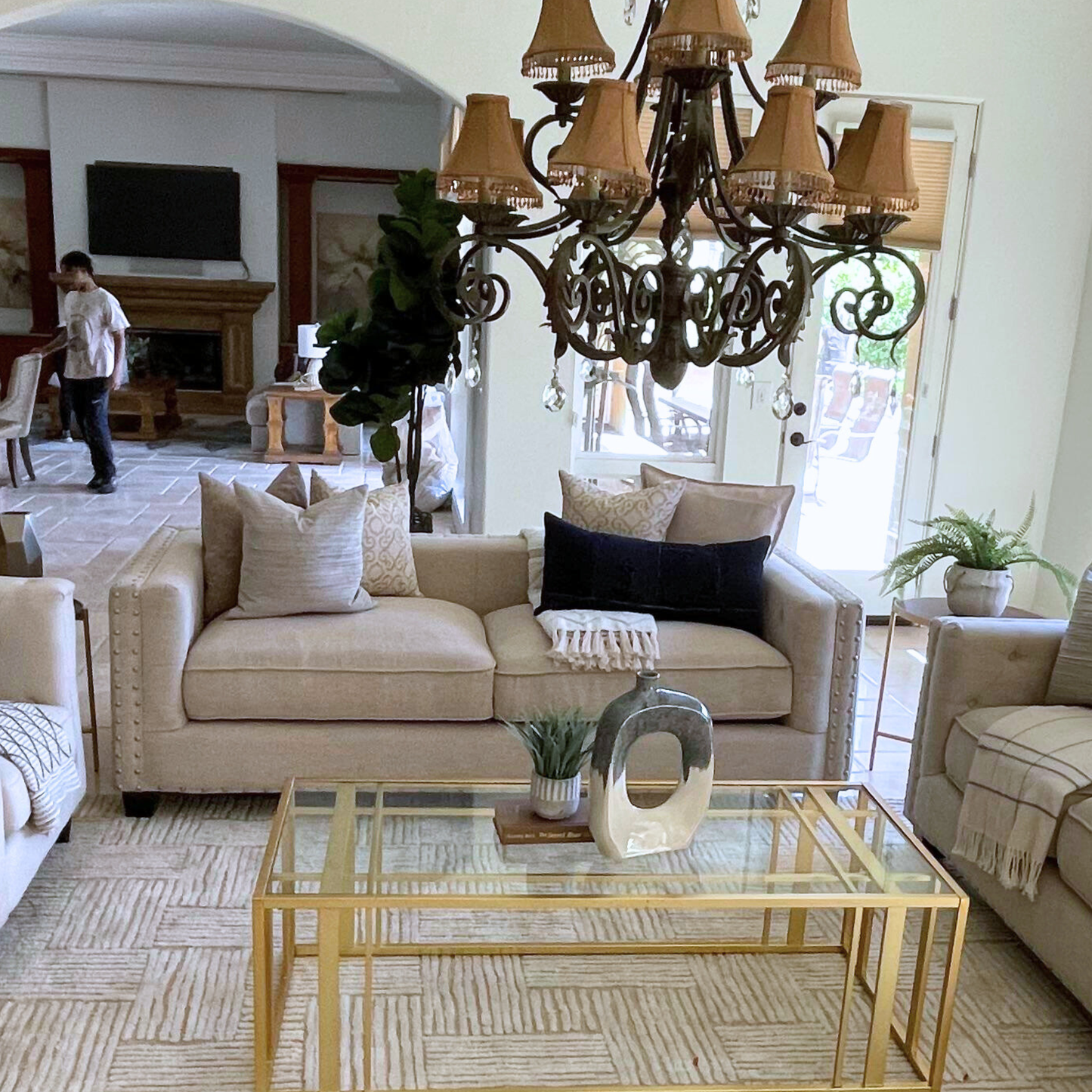 Living room with beige sofa, chandelier, and glass coffee table.