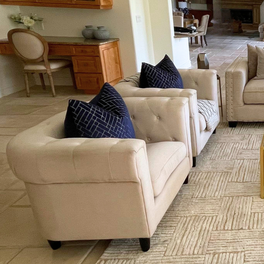 Cream tufted arm chairs in a staged living room