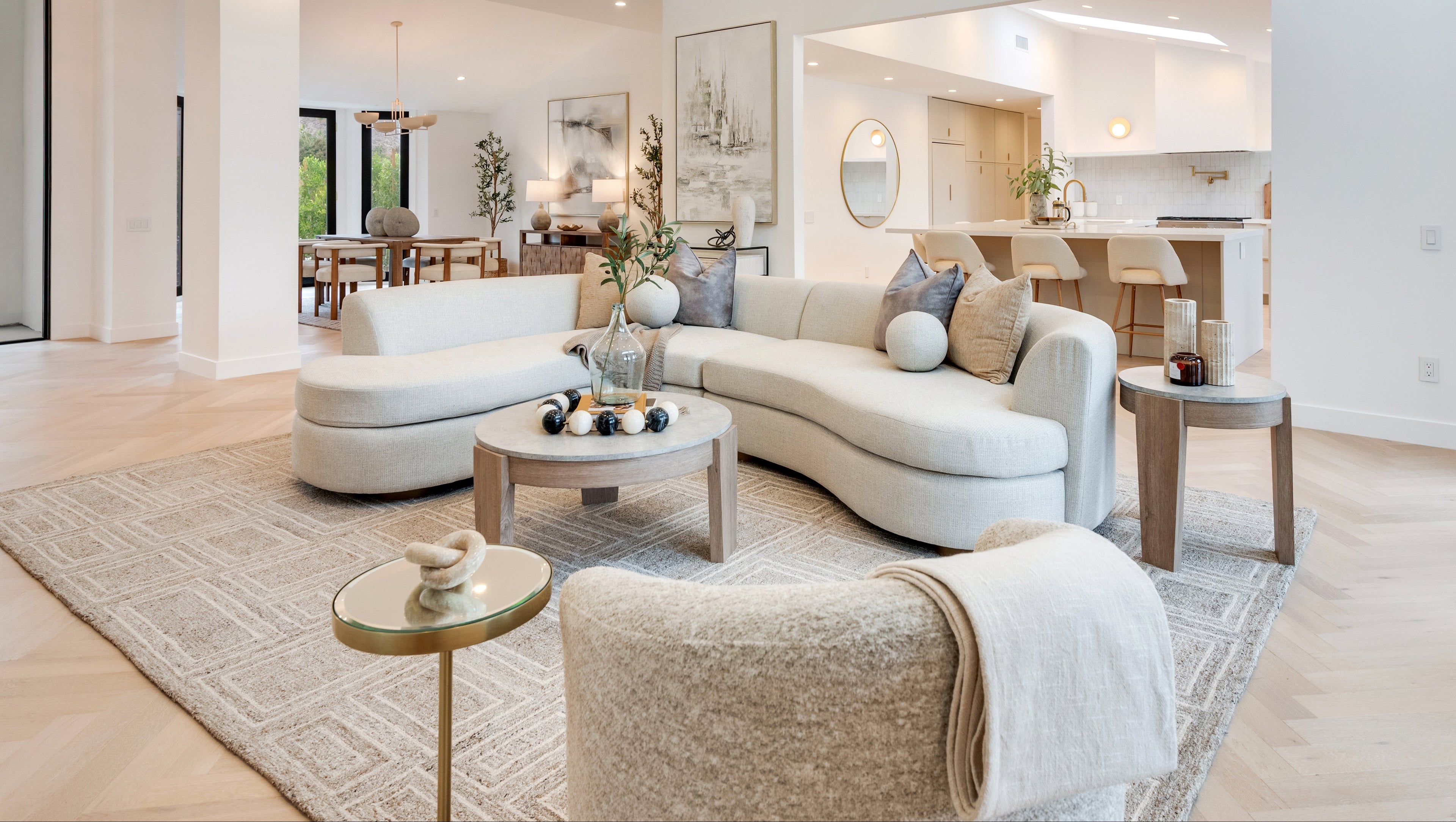 Modern living room with cream sofa, coffee table, end tables, pillows, and decor