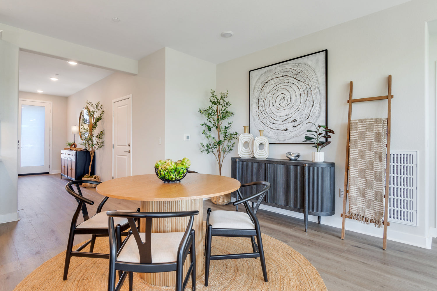 Modern dining room with round table and chairs, decorative wall art, and a sideboard.