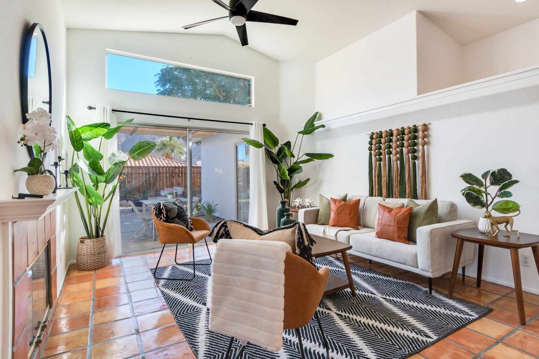 Modern living room with white sofa, brown chairs, and decorative plants.