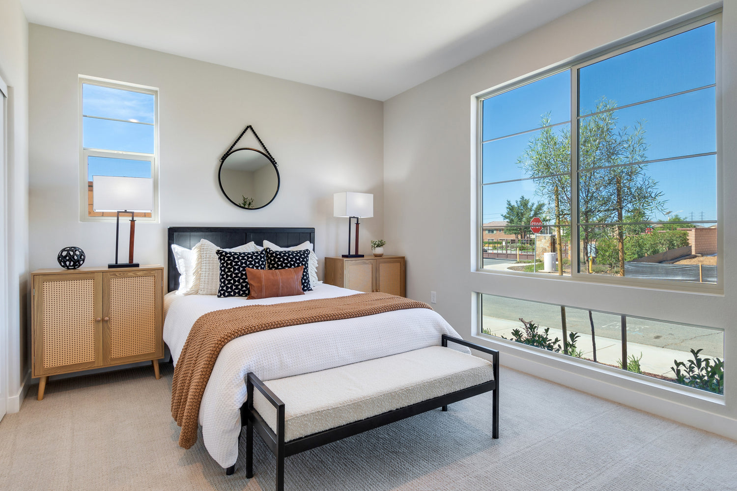 Modern bedroom with a large window, bed, and side tables.